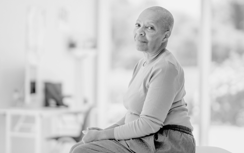 A woman sitting resiliently, embodying strength and courage as she faces her battle with cancer.