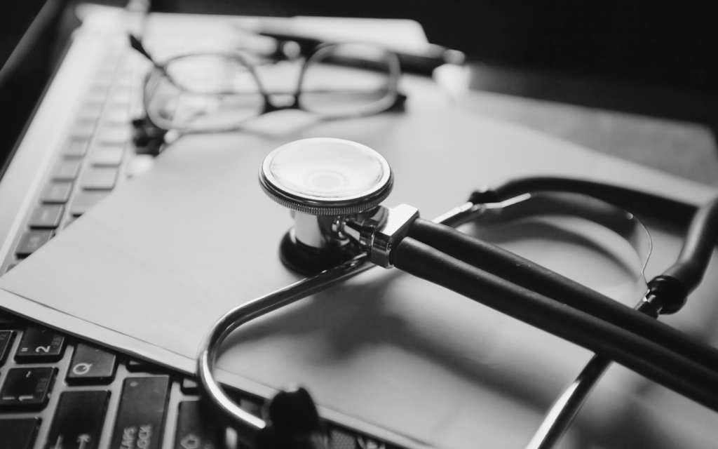 Stethoscope and glasses resting on doctor's keyboard.
