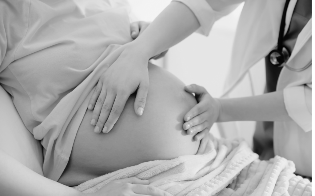 An obstetrician examining a pregnant woman's belly during a prenatal check-up.