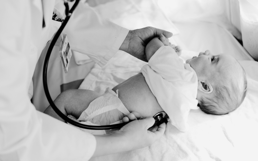 A close-up photo of a doctor's hands carefully examining a newborn baby.