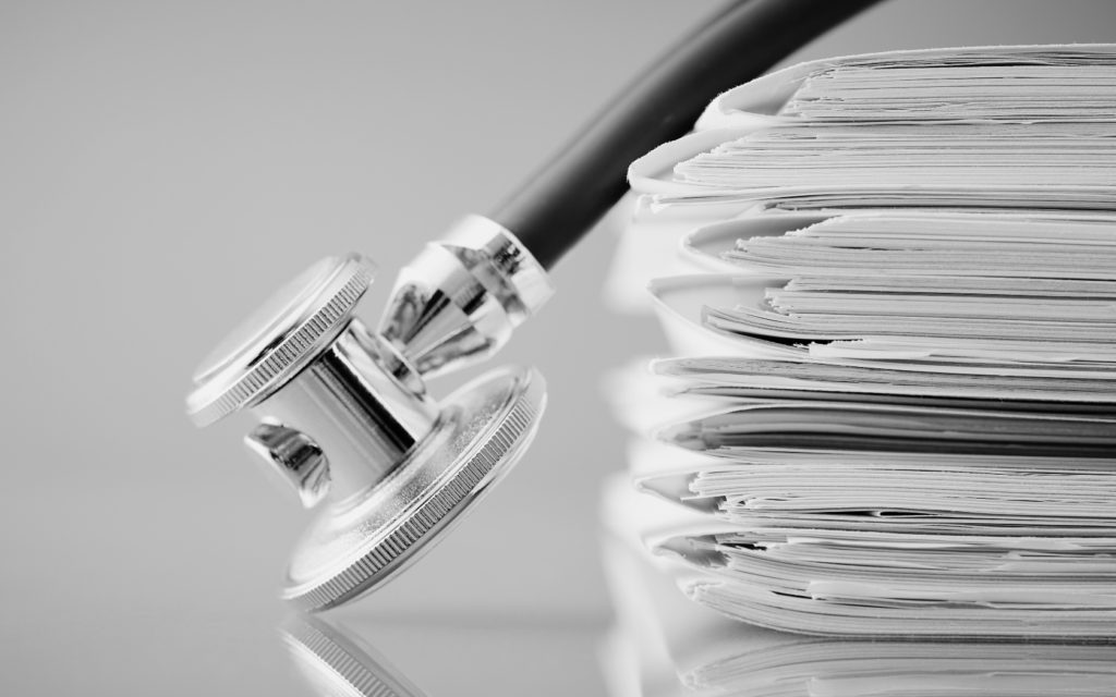 A stethoscope lying next to a stack of medical records.