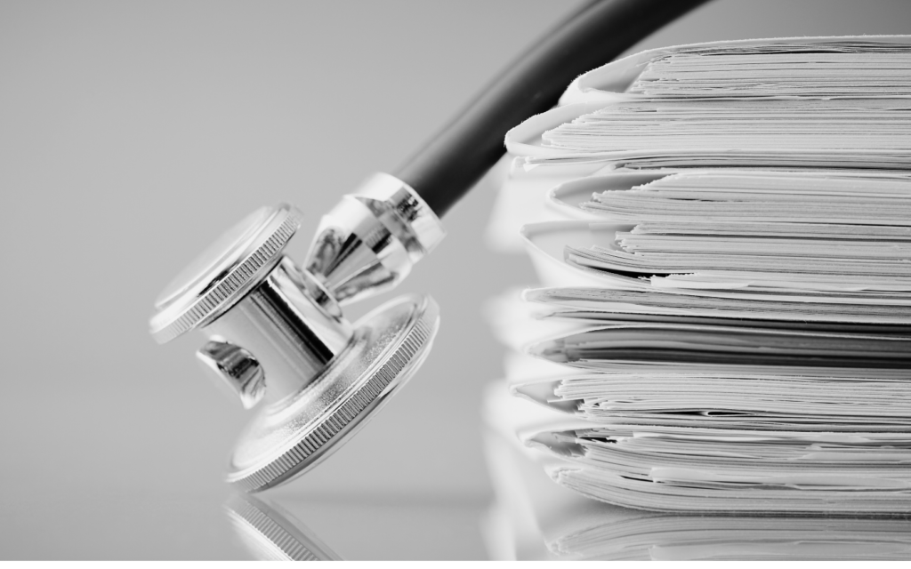 Stack of medical records next to a stethoscope.