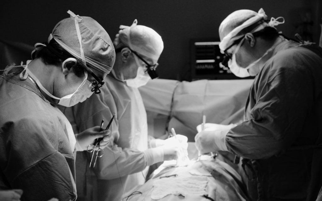 Three surgeons in an operating room performing a procedur.